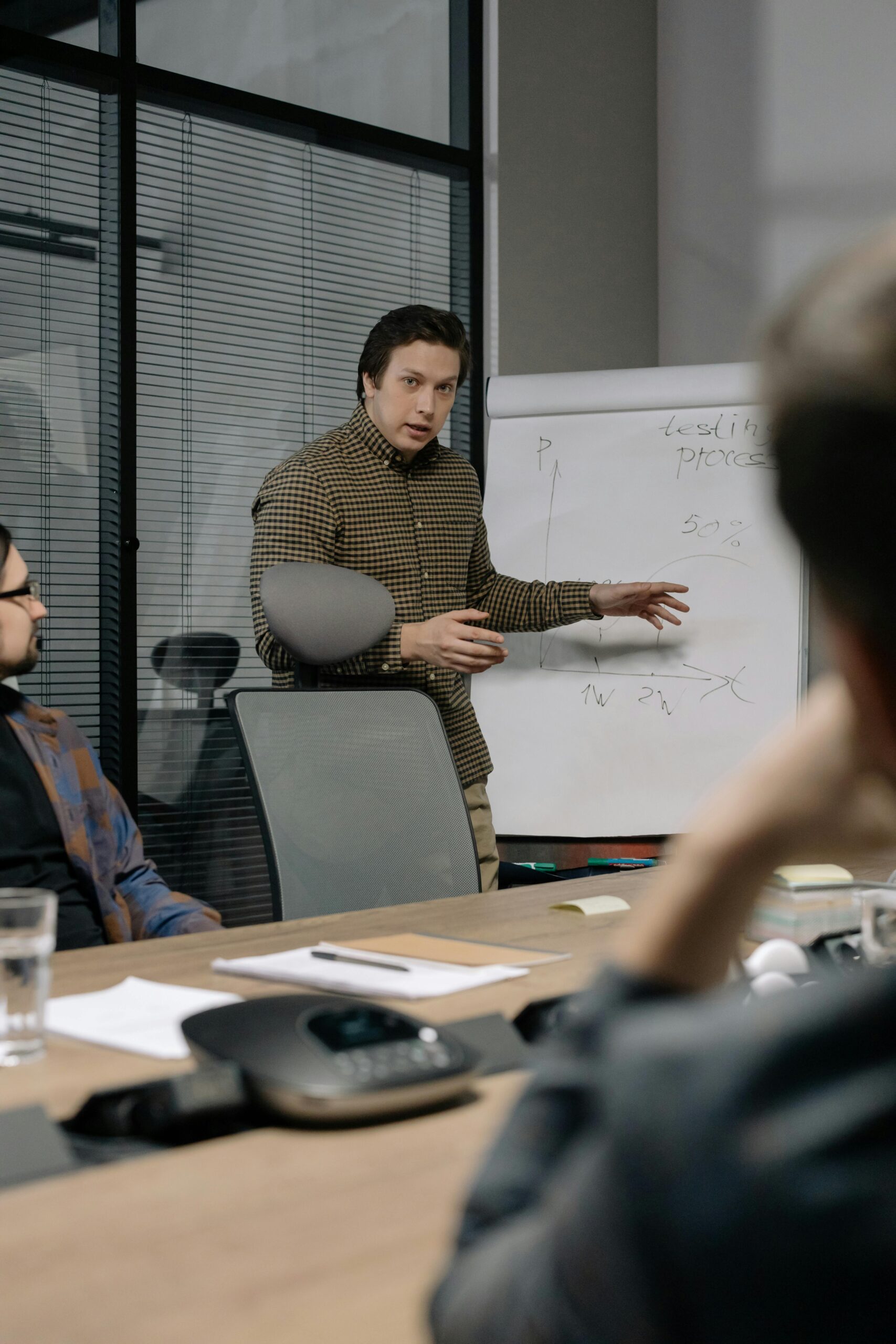 Businessman giving a presentation to colleagues in modern office setting, emphasizing teamwork and communication.